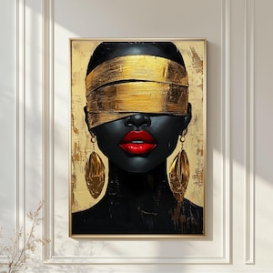 May include: A framed portrait of a person with dark skin, red lips, and gold earrings. The person's eyes are covered with gold bands. The background is gold with textured brushstrokes. The artwork is displayed on a white wall.