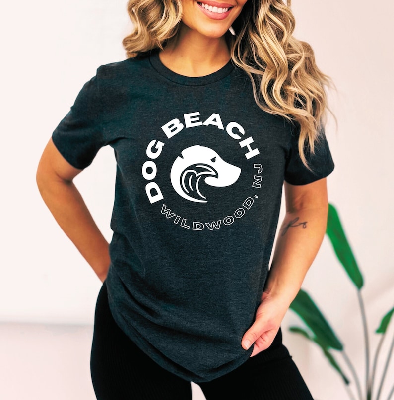 May include: A dark grey t-shirt with a white graphic of a dog head inside a circle. The circle says "Dog Beach Wildwood, NJ".
