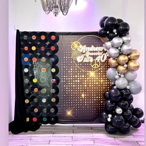 Puede incluir: Un tel&oacute;n de fondo negro y dorado con un dise&ntilde;o de bola de discoteca y el texto "Andrew Groovin' Into 40". Un arco de globos negro, plateado y dorado se encuentra en el lado derecho de la imagen.