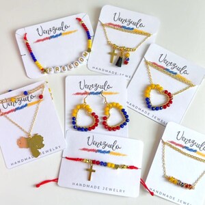 Peut inclure: Assortiment de bijoux faits main aux couleurs du drapeau v&eacute;n&eacute;zu&eacute;lien&nbsp;: jaune, bleu et rouge. Les bijoux comprennent des colliers, des bracelets, des boucles d&rsquo;oreilles et un bracelet &agrave; breloques avec le mot &laquo;&nbsp;FREEDOM&nbsp;&raquo; &eacute;crit en perles blanches.