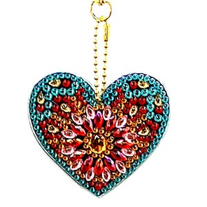 May include: A heart-shaped charm with a gold chain and clasp. The charm is embellished with red, orange, and teal-colored rhinestones. The center of the heart features a cluster of larger, faceted red and orange gems.