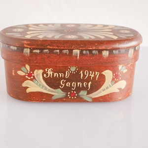 Puede incluir: Una caja de madera ovalada con un diseño floral pintado y el texto "Anno 1947 Gagnef".