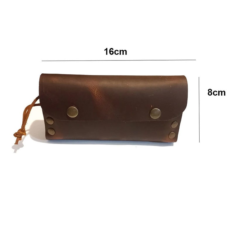 Puede incluir: Una cartera de cuero marr&oacute;n con cierre de solapa y cord&oacute;n de ajuste. La cartera tiene un aspecto desgastado y est&aacute; decorada con remaches y broches de metal. Mide 16 cm por 8 cm.