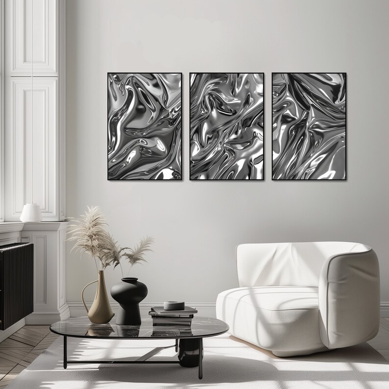 Wohnzimmerszene mit einem Sessel und einem niedrigen Tisch, der mit Büchern und Vasen dekoriert ist. An der Wand sieht man 3 schwarze Rahmen, die eine abstrakte und unique Plakat-Serie zeigen. Die Motive zeigen verschiedene Alu-Strukturen.