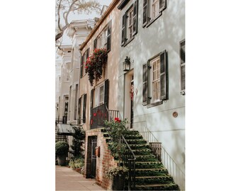 May include: A row of historic brick houses with green and white paint, black shutters, and a red flower box. The house on the right has a wooden door with a wreath and a set of steps leading up to it.