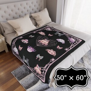 May include: Black and pink fleece throw blanket with a spiderweb design and cute spider illustrations. The blanket measures 50 inches by 60 inches.