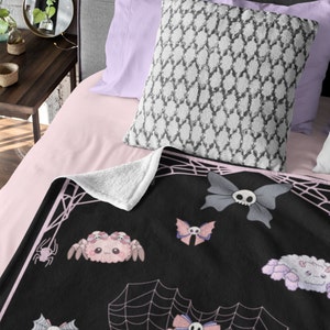 May include: Black and pink fleece throw blanket with a spiderweb design and cute cartoon spiders with bows and skulls.