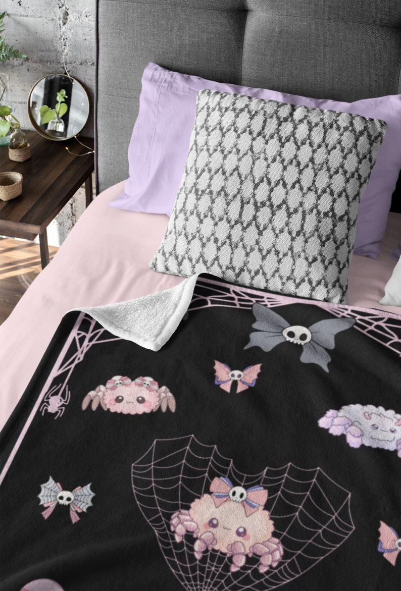 May include: Black and pink fleece throw blanket with a spiderweb design and cute cartoon spiders with bows and skulls.