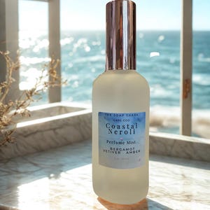 May include: A frosted glass perfume mist bottle with a silver cap. The label reads "Coastal Neroli Perfume Mist" with "Bergamot, Vetiver, Amber" listed below. The bottle is 5 fl oz / 150 ml.