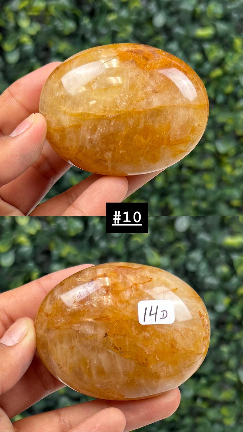 May include: Two polished, oval-shaped gemstones with a golden-yellow hue. The stones have a smooth, glossy surface with internal patterns. The image includes the text "#10" and "14D".