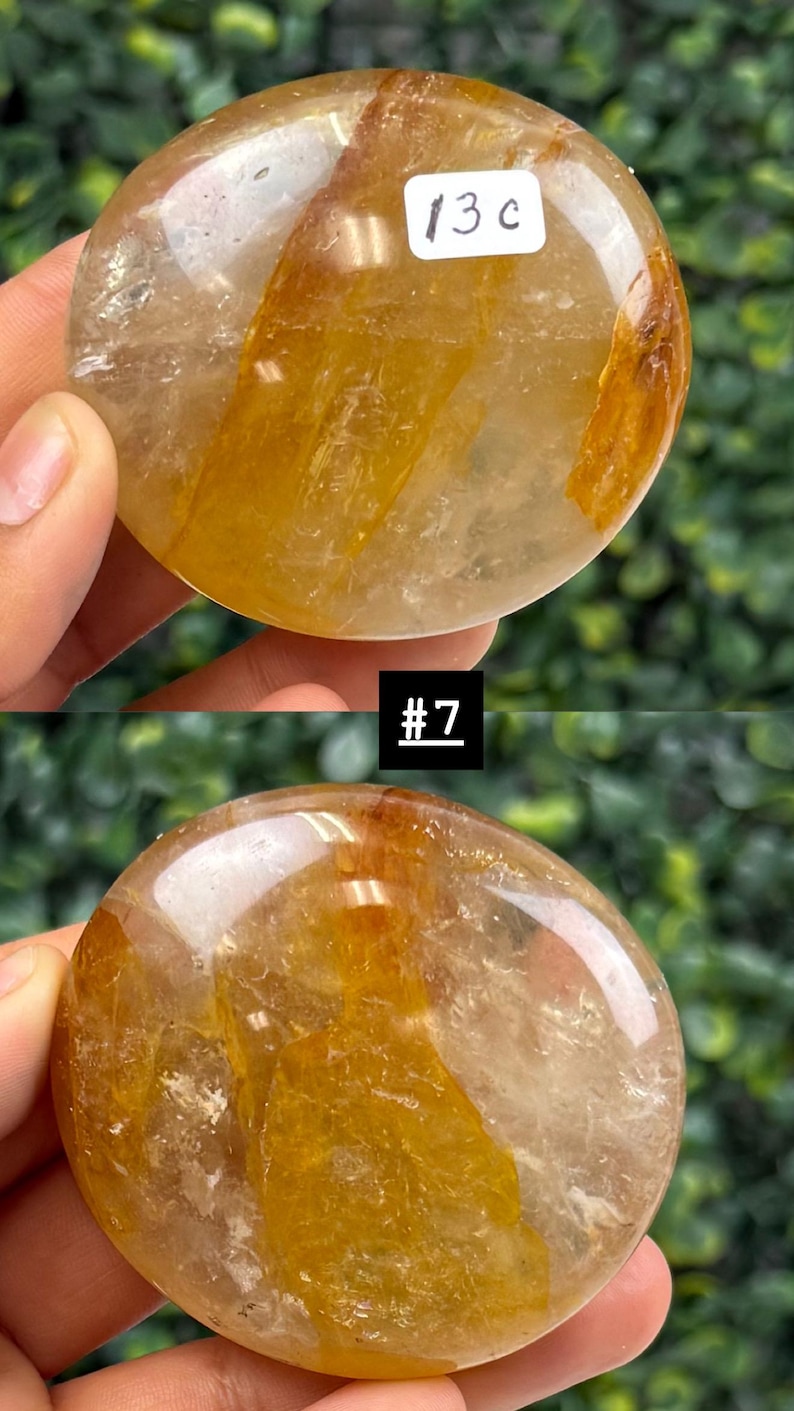 May include: Two polished, round gemstones with a golden-yellow and clear appearance. The stones have a smooth, reflective surface. One stone has the text "13 c" on a white label. The other stone has the text "#7" on a black label.