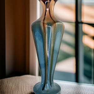 Peut inclure: Un vase en verre iridescent bleu et brun avec un sommet évasé et une base arrondie.