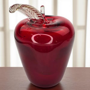 以下が含まれることがあります： 深紅色の装飾用ガラス製リンゴ。リンゴは透明なガラスの茎と葉のディテールが特徴で、エレガントさを添えています。光沢のある仕上がりは鮮やかな色を際立たせ、印象的なインテリア装飾品となっています。