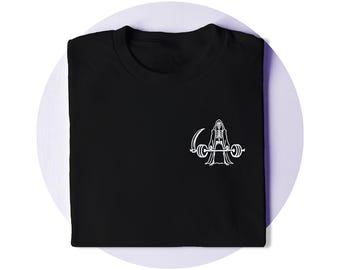 Op de afbeelding: Een zwart t-shirt met een witte afbeelding op de borst. Het ontwerp toont een skelet met een kap en mantel, dat in de ene hand een zeis vasthoudt en met de andere hand een zware halter met gewichten aan de uiteinden optilt.