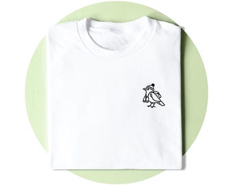 Op de afbeelding: Een wit t-shirt met een kleine zwarte lijntekening op de borst. De afbeelding toont een vogel die een muts en een rugzak draagt en een verrekijker vasthoudt. Het t-shirt heeft een ronde hals en korte mouwen.