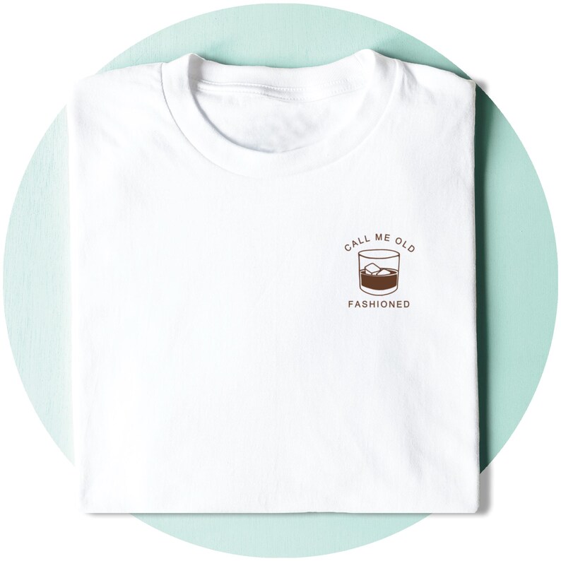 May include: White t-shirt with a brown graphic of a glass of whiskey with ice cubes and the text "Call me old fashioned".