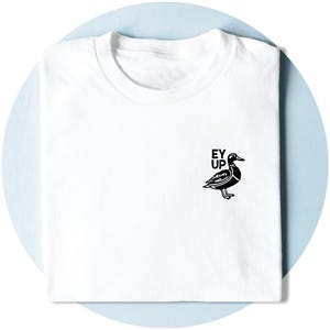 May include: A white short-sleeved t-shirt featuring a black graphic of a duck on the right side of the chest. Above the duck, the text "EY UP" is printed in a bold, black sans-serif font. The shirt is folded neatly with a crew neckline.