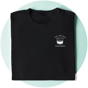 May include: Black t-shirt with white text that reads "Call me old fashioned" and a graphic of a glass of whiskey with ice cubes.