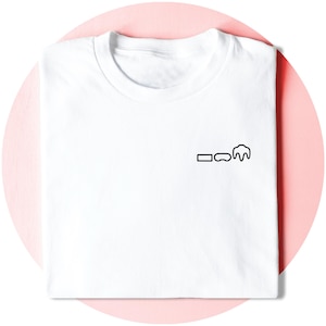 以下が含まれることがあります： 胸に小さな黒いグラフィックが付いた白いTシャツ。グラフィックは長方形、楕円、雲のような形で構成されています。シャツはピンク色の背景にきれいに折りたたまれています。