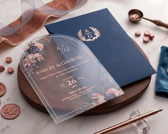Invitación de boda acrílica con arco floral, sobre azul marino y monograma dorado. Elegante tarjeta de invitación transparente. Lujo moderno.