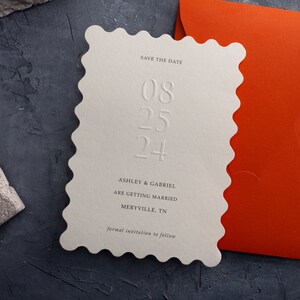Golvende rand reliëf: Save the Date met verbrande oranje envelop, minimale boekdruk trouwkaart, blinde inscriptie, moderne uitnodiging