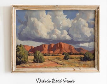 May include: A framed landscape painting depicting a red rock formation with a large, fluffy cloud in the sky. The painting is in a light wood frame.