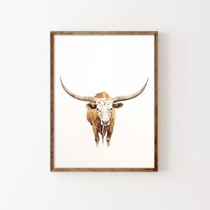 May include: A watercolour painting of a brown and white Texas Longhorn steer with large horns. The steer is facing the viewer and has a white face with brown spots.