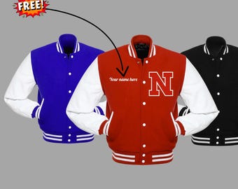 May include: Three varsity jackets in blue, red, and black with white sleeves. The red jacket has a large white "N" and the text "Your name here". The jackets have a button-up front and striped cuffs and hem. The word "FREE!" is in a starburst.