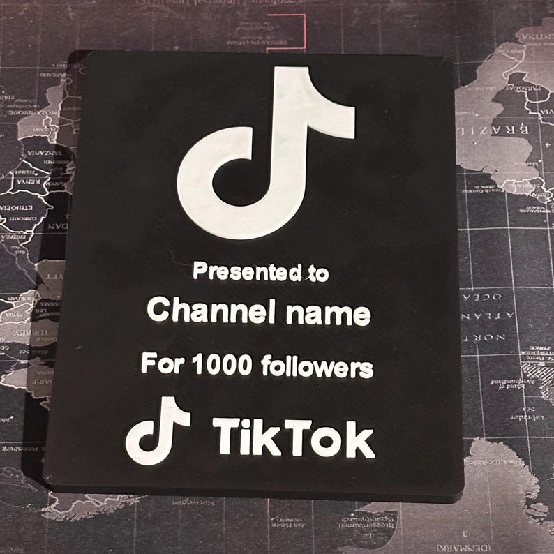 Peut inclure: Plaque noire avec un logo TikTok blanc et le texte "Pr&eacute;sent&eacute; &agrave; Channel name Pour 1000 abonn&eacute;s TikTok".