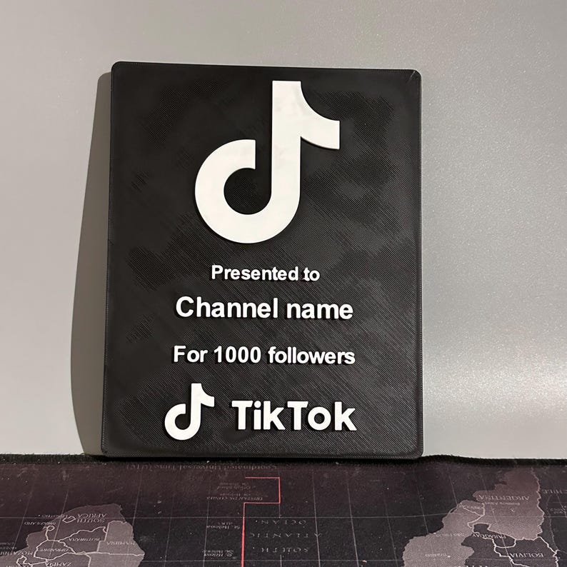 Peut inclure: Plaque noire avec un logo TikTok blanc et le texte "Pr&eacute;sent&eacute; &agrave; Channel name Pour 1000 abonn&eacute;s"