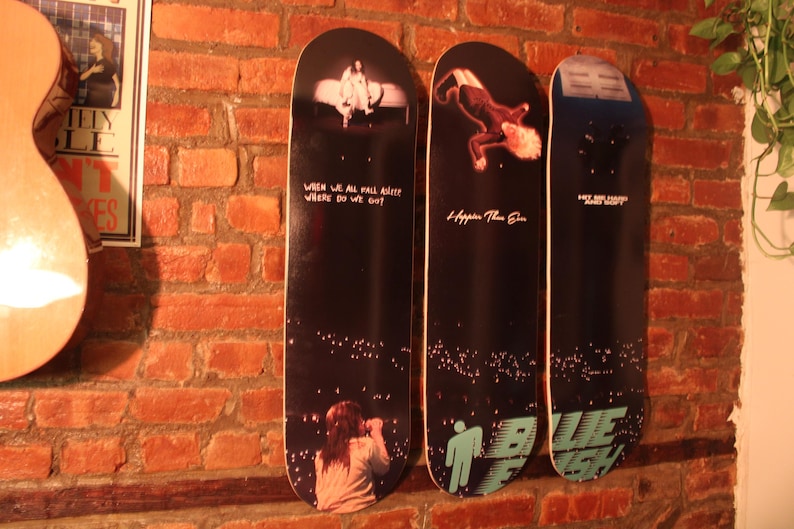 Puede incluir: Tres tablas de skate negras y blancas con dise&ntilde;os gr&aacute;ficos. La primera tabla tiene el texto "When we all fall asleep where do we go?" La segunda tabla tiene el texto "I hope you're the one." La tercera tabla tiene el texto "Why are you so sad?" y un gr&aacute;fico azul y blanco.