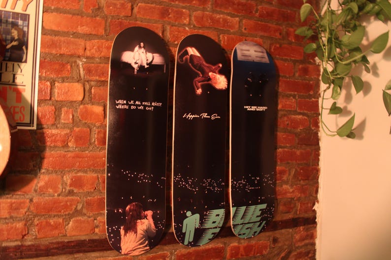 Puede incluir: Tres tablas de skate negras y blancas con dise&ntilde;os diferentes. La primera tabla tiene el texto "When we all fall asleep where do we go?" La segunda tabla tiene el texto "Happier Than Ever". La tercera tabla tiene el texto "Why are things so heavy?" y "Blue Banisters".