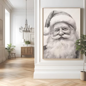 May include: A framed black and white portrait of Santa Claus. The artwork depicts Santa with a long white beard, round glasses, and a traditional hat. The portrait is displayed in a room with a chandelier, wooden floors, and a plant.