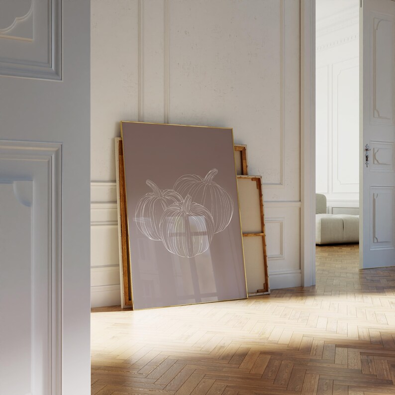 May include: A framed print with a light brown background and a white outline drawing of three pumpkins.