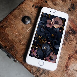May include: A white smartphone with a floral phone case. The case features a dark background with pink and gold flowers.