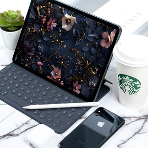May include: A black iPad with a floral wallpaper, a black keyboard, a white stylus, a black iPhone with a white Apple logo, and a white coffee cup with a green Starbucks logo.
