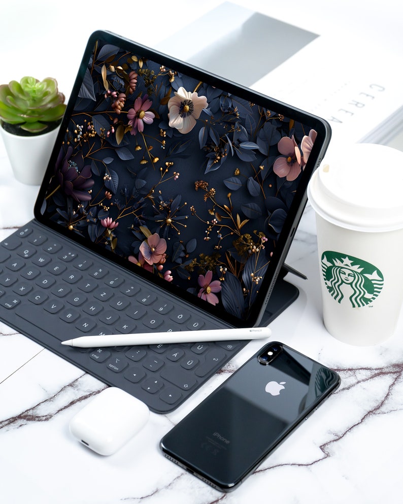May include: A black iPad with a floral wallpaper, a black keyboard, a white stylus, a black iPhone with a white Apple logo, and a white coffee cup with a green Starbucks logo.