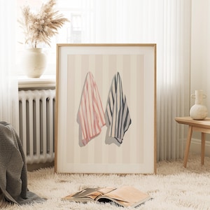 May include: A framed print of two striped towels hanging on a wall with a striped background. The towels are pink and white and black and white.