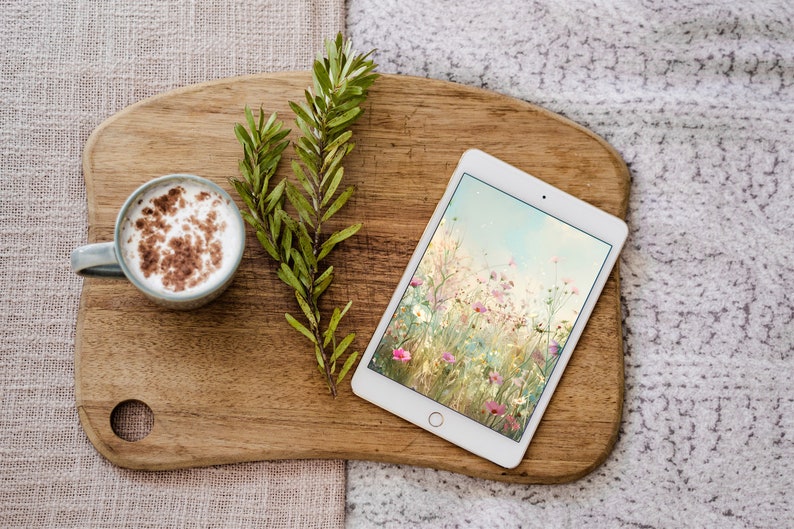 May include: A wooden cutting board with a cup of coffee, a tablet with a floral screen saver, and a sprig of green leaves.