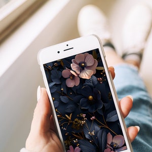 May include: A white smartphone with a floral wallpaper. The wallpaper features pink and blue flowers with gold accents on a dark background.