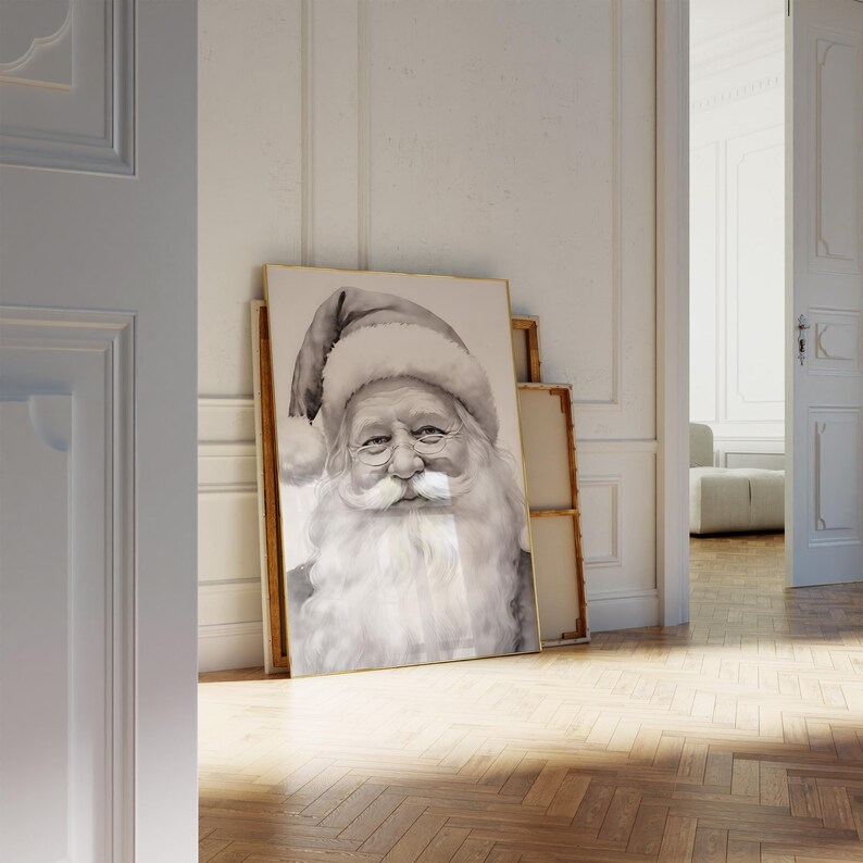 May include: A black and white watercolor print of Santa Claus, wearing a traditional hat and a long white beard. The artwork is displayed in a gold frame, leaning against a wall. The image is in a room with a wooden floor.