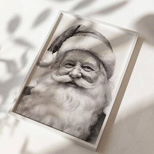 May include: Black and white framed print of Santa Claus. The portrait features Santa with a long white beard, glasses, and a traditional hat. The image is set in a white frame, creating a classic holiday decoration.
