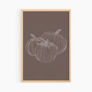 May include: A framed print with a brown background and a white line drawing of three pumpkins.
