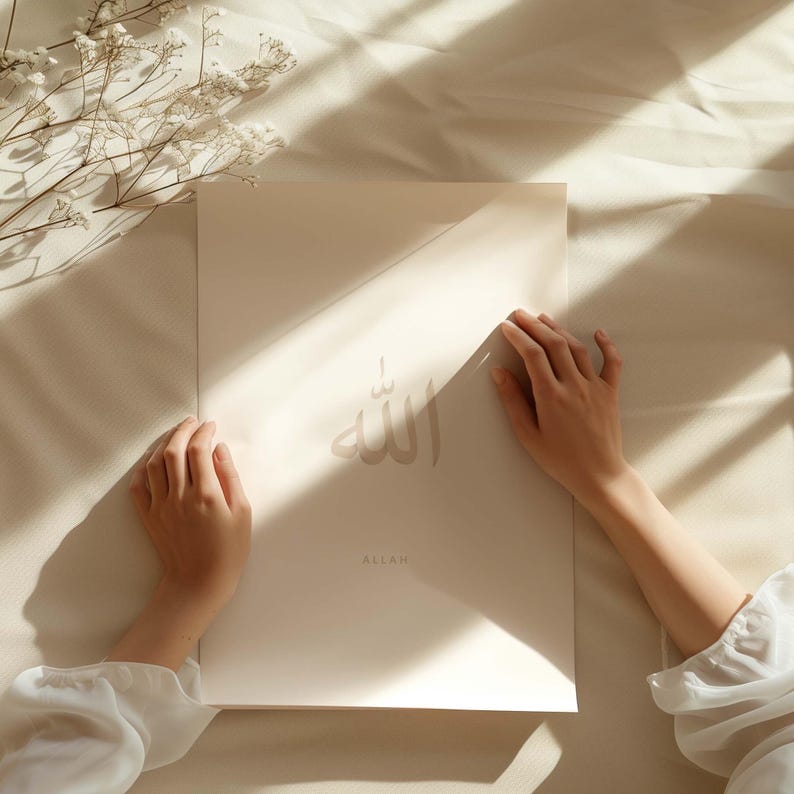 May include: A white poster featuring the Arabic word for "Allah" in brown calligraphy. The word "Allah" is written in English beneath the calligraphy. The poster is being held by a person's hands.