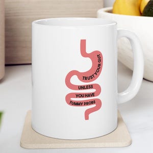 May include: A set of three ceramic mugs with a speckled, matte finish. The mugs are in shades of cream, light gray, and dark gray. Each mug has a simple, minimalist design, perfect for coffee or tea.