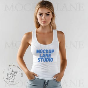 Può includere: Un top bianco senza maniche con una grafica blu che dice "Mockup Lane Studio". La modella indossa il top con jeans blu.