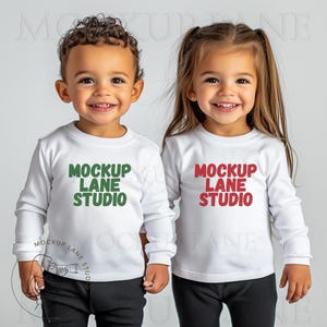 May include: Two children wearing white long-sleeved shirts with the text "MOCKUP LANE STUDIO" in green and red on the front. The child on the left is wearing a green shirt and the child on the right is wearing a red shirt.