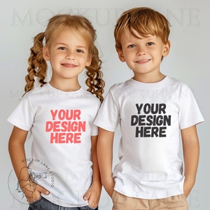 May include: Two children wearing white t-shirts with the text "Your design here" printed on them. The girl is on the left and has blonde hair in braids. The boy is on the right and has blonde hair. Both children are smiling.
