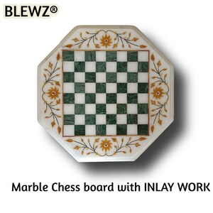May include: Octagonal marble chess board with green and white checkered squares. The board features floral inlay work in gold and brown tones around the edges. The text "Marble Chess board with INLAY WORK" is displayed below the board.