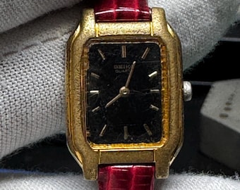 Vintage Seiko ladies quartz watch with a black dial and gold tone. Well worn patina